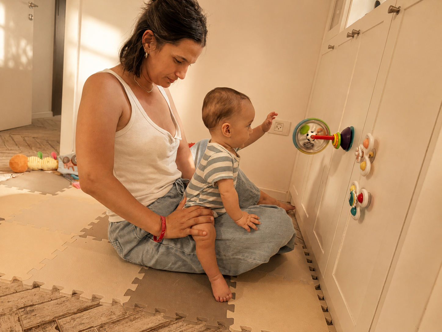 A mother on the floor with her baby during unhurried play in warm afternoon light